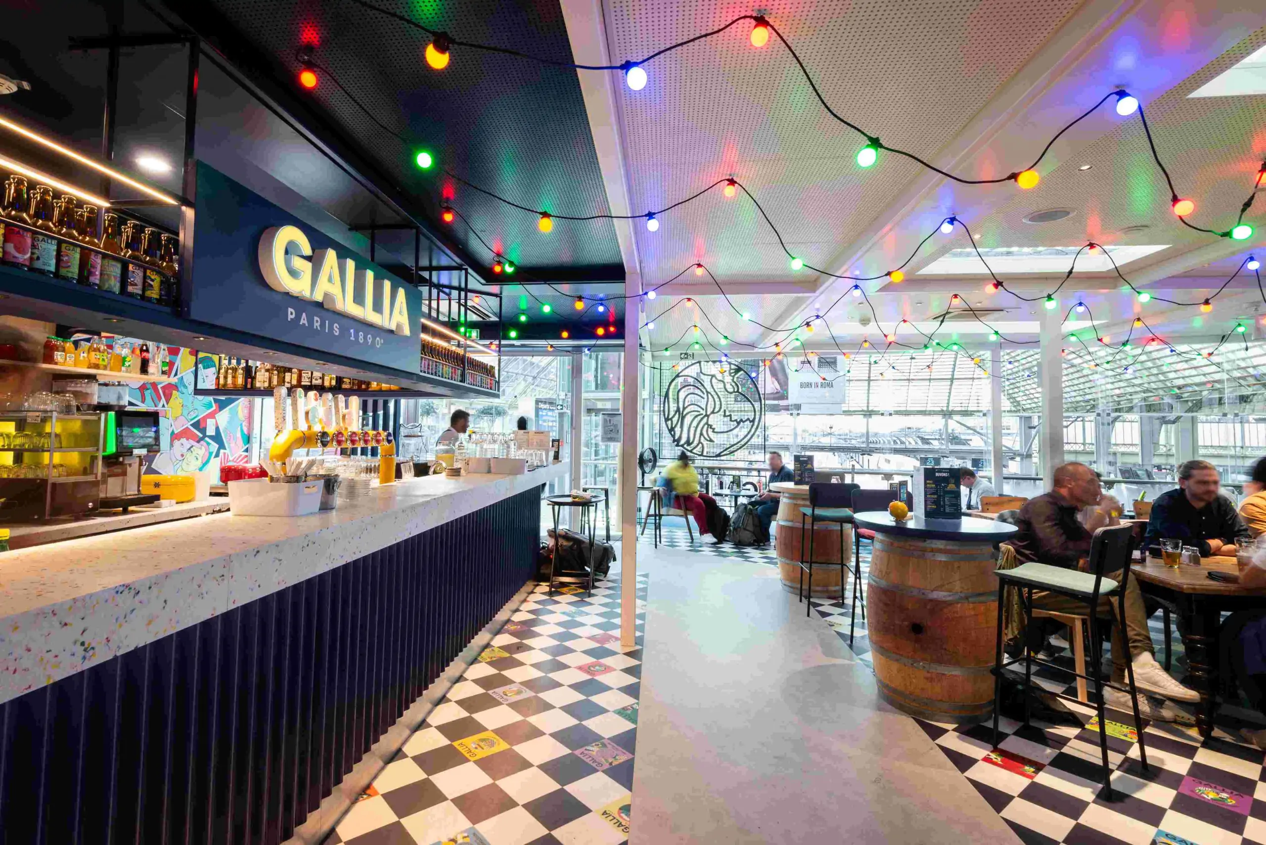 Bar GALLIA Paris avec comptoir, tireuses à bière et guirlandes lumineuses dans un espace convivial.